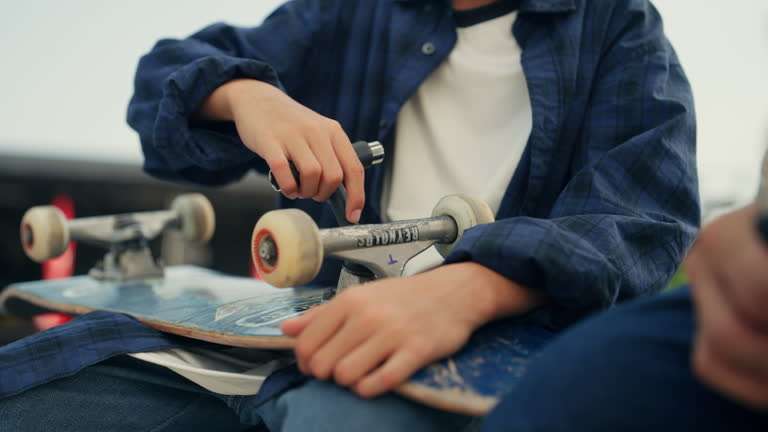 Person adjusting the wheel of a longboard, preparing for a ride.