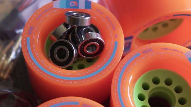 Bright orange longboard wheels with bearings ready for assembly.