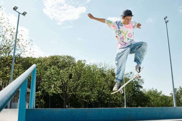 Young man does a trick on his longboard in a sunny skate park.