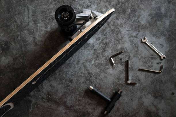 Longboard and various tools scattered on a dark concrete floor.